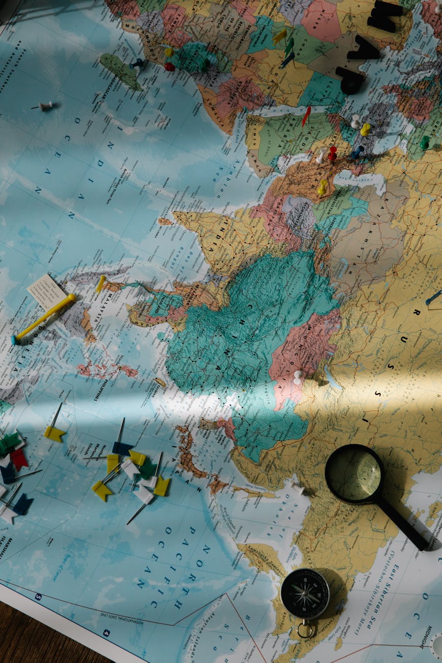 Exploration tools, including a compass and magnifying glass, placed on a colorful world map.