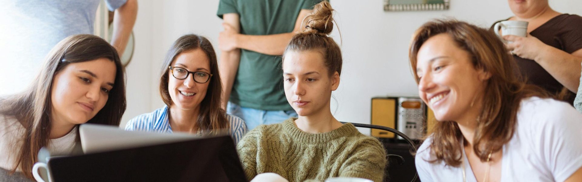 A diverse group of adults at work, enjoying a casual meeting indoors with focus and smiles.