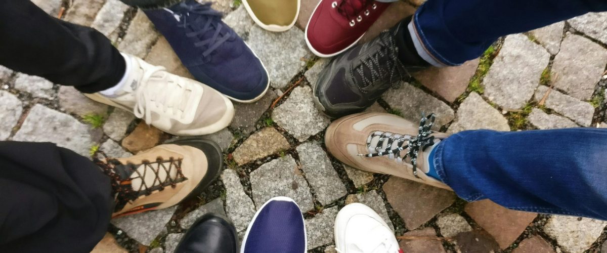 Circle of sneakers on cobblestone pavement representing diversity and urban fashion.