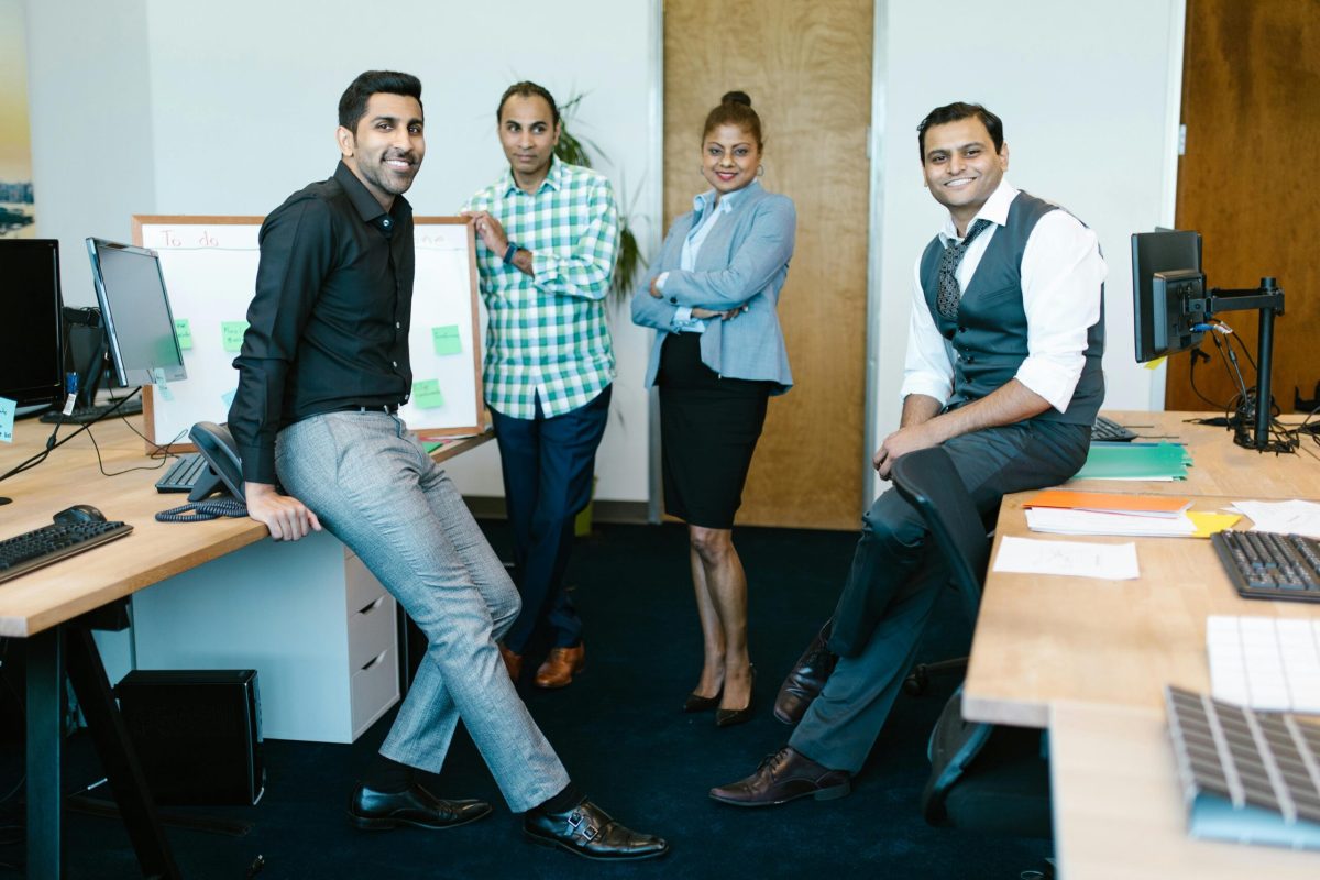 Group of happy business professionals posing together in a modern office setting.